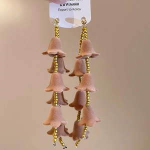 Détail de boucles d'oreilles pendantes vintage avec fleurs floquées brunes et perles dorées