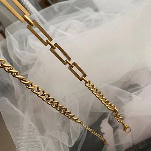 Close-up of golden titanium Cuban chain on white lace fabric showing dual link design