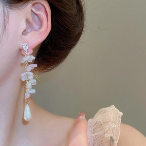 Detail of elegant pink resin flower drop earrings with dangling pearls and gold chains