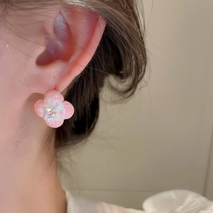 Close-up of sweet pink floral earrings with cats eye stone and zircon on female ear