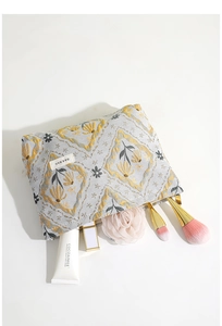 Close-up of jacquard floral makeup bag with cosmetics and brushes on white background