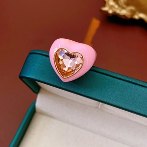 Detailed macro view of heart-shaped ring with pink enamel and sparkling center gemstone