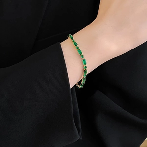Detalle de pulsera de circonita verde esmeralda bañada en oro en la muñeca