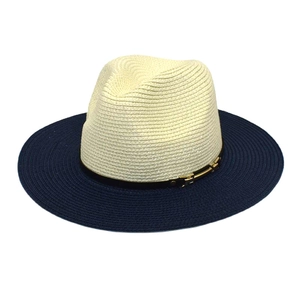 Détail d'un chapeau de paille bicolore avec calotte ivoire et boucle dorée élégante