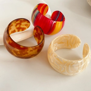 Detailed view of three resin bangles in tortoiseshell, striped, and marble patterns