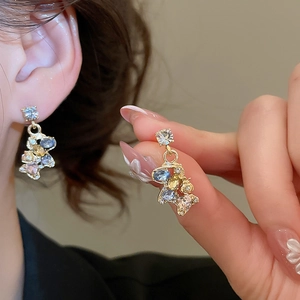 Detailed view of luxury gold horse pendant earrings with blue and yellow crystals