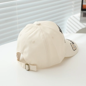 Detail of happy bear embroidery and metal buckle on kids beige cotton baseball cap