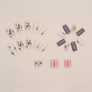 Pink and purple press-on nails with leaf pattern ink smudge art on a beige background