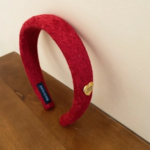 Detail of red tweed headband featuring a gold heart pendant and handmade woven label