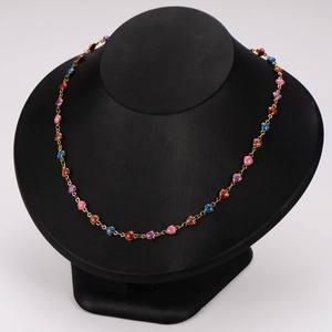 Golden necklace with colorful glitter heart and round beads on jewelry display stand