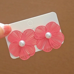 Close-up of pink flower earrings with a central pearl and delicate filigree petals