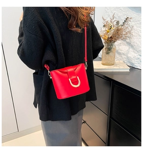 Detail of red PU leather bucket bag with prominent gold D-ring hardware closure