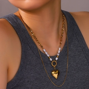 Double-layered gold heart pendant necklace with white pearls and textured ring accent