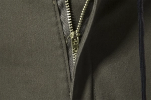 Dettaglio macro della cerniera in metallo e del tessuto in twill dei pantaloni uomo