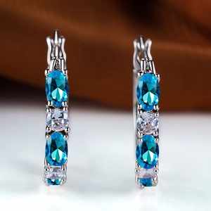 Close-up of silver hoop earrings featuring alternating blue topaz and white cubic zirconia stones
