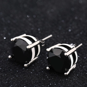 Detailed macro view of black zircon earrings with silver four-claw setting and striped base