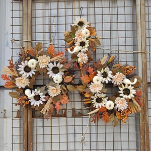 Detailed view of autumn wreaths with white pumpkins, sunflowers, and maple leaves on mesh