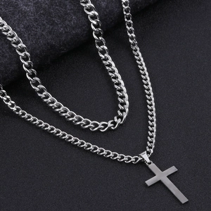 Macro detail of silver double-layered hip-hop necklace with cross pendant and cuban chain