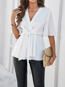 Détail du haut cache-cœur élégant avec col en V et ceinture nouée en tissu blanc