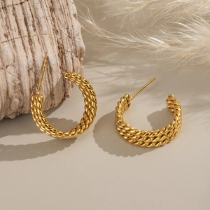 Three-layer twisted gold C-shaped hoop earrings on elegant minimalist beige background