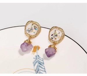 Macro shot of vintage gold earrings with purple natural stones on a decorative ceramic plate