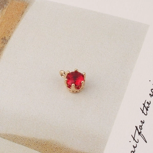 Macro detail of red gemstone pendant with gold crown setting and micro zircon accents