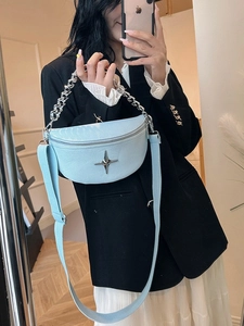 Light blue half-moon crossbody bag with silver chain and star ornament on a model