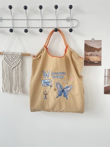Detail of blue butterfly embroidery and Butterfly Poetry text on khaki oxford tote bag