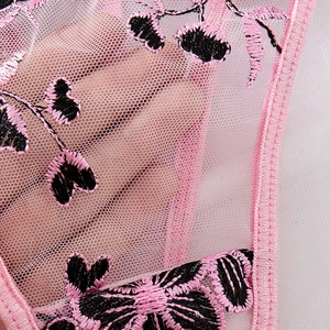 Detailed close-up of sheer pink mesh fabric with intricate floral embroidery details