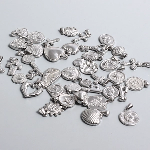 Detailed view of various vintage stainless steel charms and pendants for DIY jewelry
