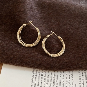 Detail of gold double-layered hoop earrings on a warm brown textured velvet surface