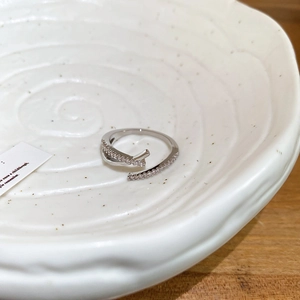 Detailed view of silver bow-shaped wrap ring with sparkling zircon stones in a tray