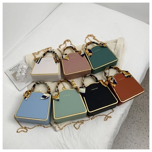 Flat lay of multiple color PU box bags with silk scarf handles and chain straps