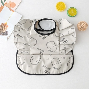 Detail of waterproof beige baby bib with winged sleeves and cute dessert patterns