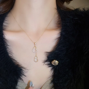 Gros plan du collier pendentif Wu Lou doré avec zircons et opale sur un mannequin