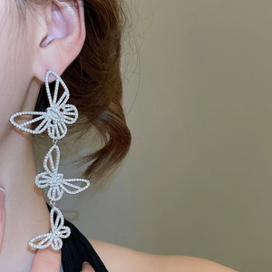 Detail of silver asymmetric butterfly drop earrings with sparkling cubic zirconia on model