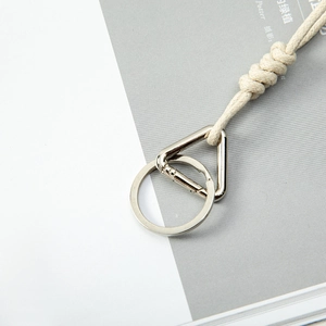 Chic beige braided rope keychain with silver spring hook on minimalist background