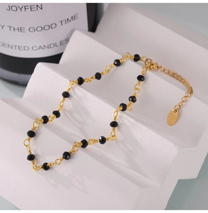 Detail of 18k gold plated stainless steel anklet with faceted black beads and clasp