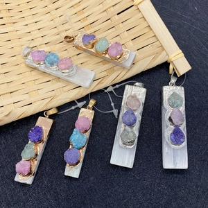 Macro shot of rectangular selenite pendants with colorful natural crystal clusters