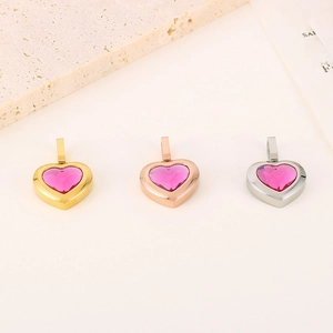 Detailed view of heart-shaped pendants in gold, rose gold, and silver with pink gemstones