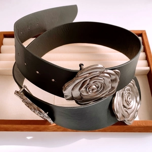 Gros plan d'une ceinture en cuir noir avec boucle rose argentée sur daim marron