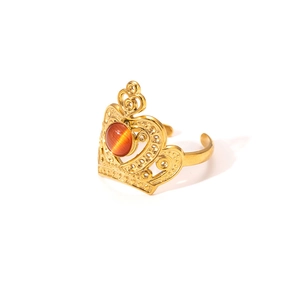 Detail of a gold crown-shaped ring featuring an orange cat eye stone and adjustable band