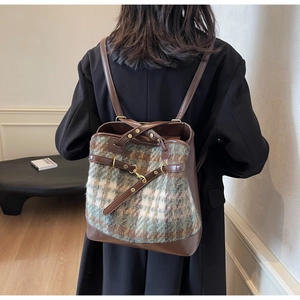 Detail of a vintage-style plaid fabric and brown faux leather patchwork backpack