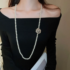 Gros plan d'un collier de perles orné d'un pendentif rose évidé serti de diamants fins