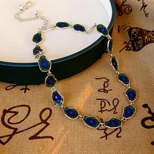 Detailed close-up of blue and green enamel lotus leaf necklace with a lobster clasp