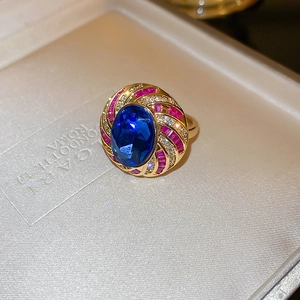 Macro shot of gold ring with oval blue gem and fan-shaped pink stones in jewelry box