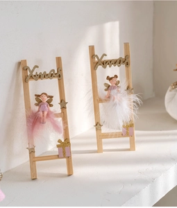 Detailed close-up of pink angel ornaments on a wooden ladder with golden stars and gifts