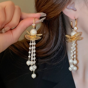 Detail of elegant gold fan earrings with cascading multi-layer pearl tassels on a model
