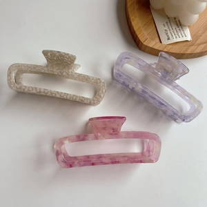 Detailed macro view of large hollow acetate hair claws with marble texture in three colors