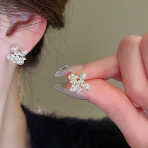 Close-up detail of silver needle pearl tassel earrings with zircons and gold metal finish
